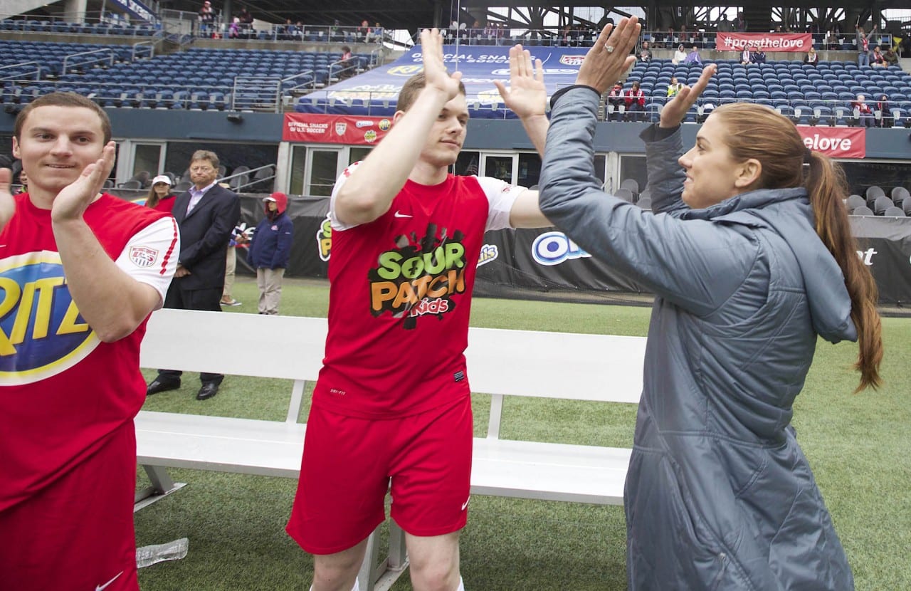 U.S. Soccer star Alex Morgan, far right, celebrates a goal while coaching a team comprised mostly of Seattle-area veterans during an exhibition soccer game at CenturyLink Field organized by the Official Snacks of U.S. Soccer (OREO, RITZ, TRIDENT, SOUR PATCH KIDS & HONEY MAID) in Seattle Wednesday April 23, 2014. The game replicated the thrills of a major international match for amateur players as part of the new #PassTheLove program to celebrate the spirit of soccer heading into the worldís largest sporting event this summer. (Stephen Brashear/AP Images for Mondelez International)