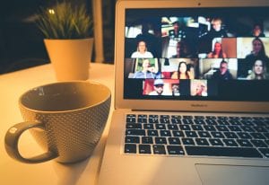 stock_virtual event_laptop screen with people and nearby coffee mug
