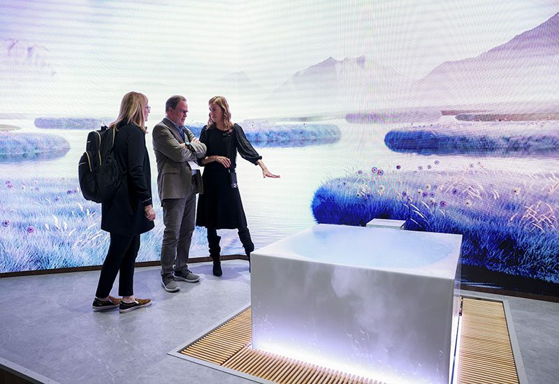 Three attendees look at the Kohler Stillness Infinity Experience Bath