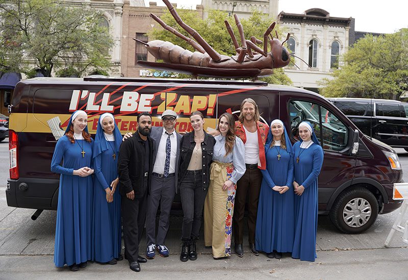 The cast of "Mrs. Davis" poses in front of an exterminator van from the show