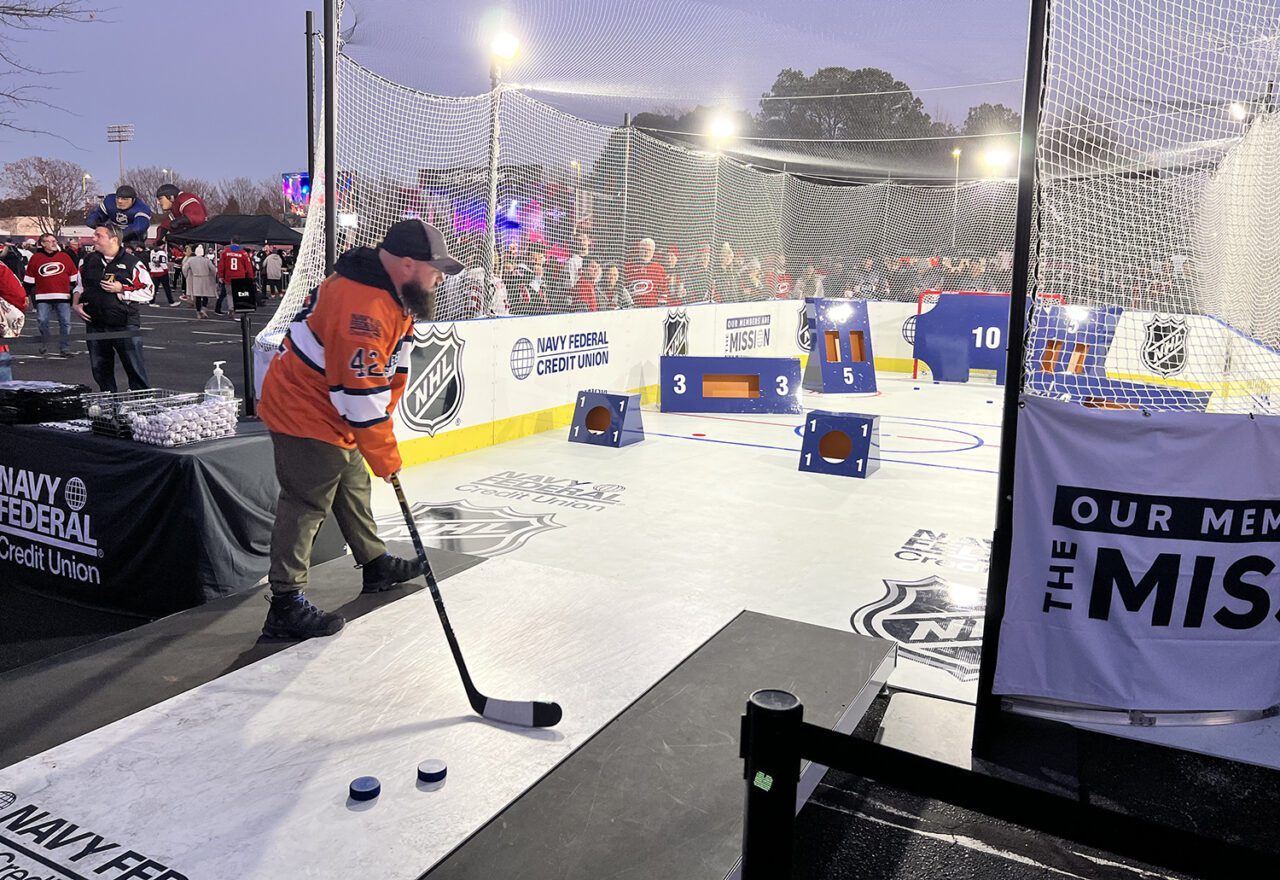 navy-federal-credit-union-nhl-2023-unionstadiumseries-pregame-fan-fest_Man swings ice hockey stick