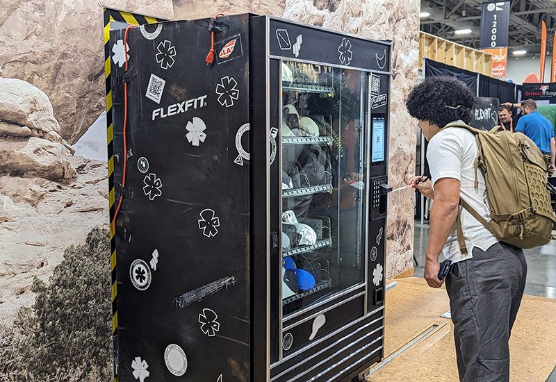 Attendee interacts with a vending machine at Flexfit's exhibit outdoor retailer 2023
