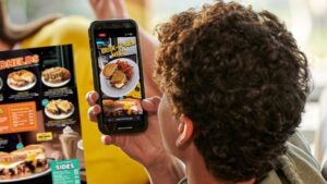 Dennys_ guy looks at AR menu with phone_2023