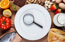 Allergy food concept. Food and empty plate with magnifier on wooden table.