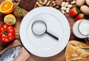 Allergy food concept. Food and empty plate with magnifier on wooden table.